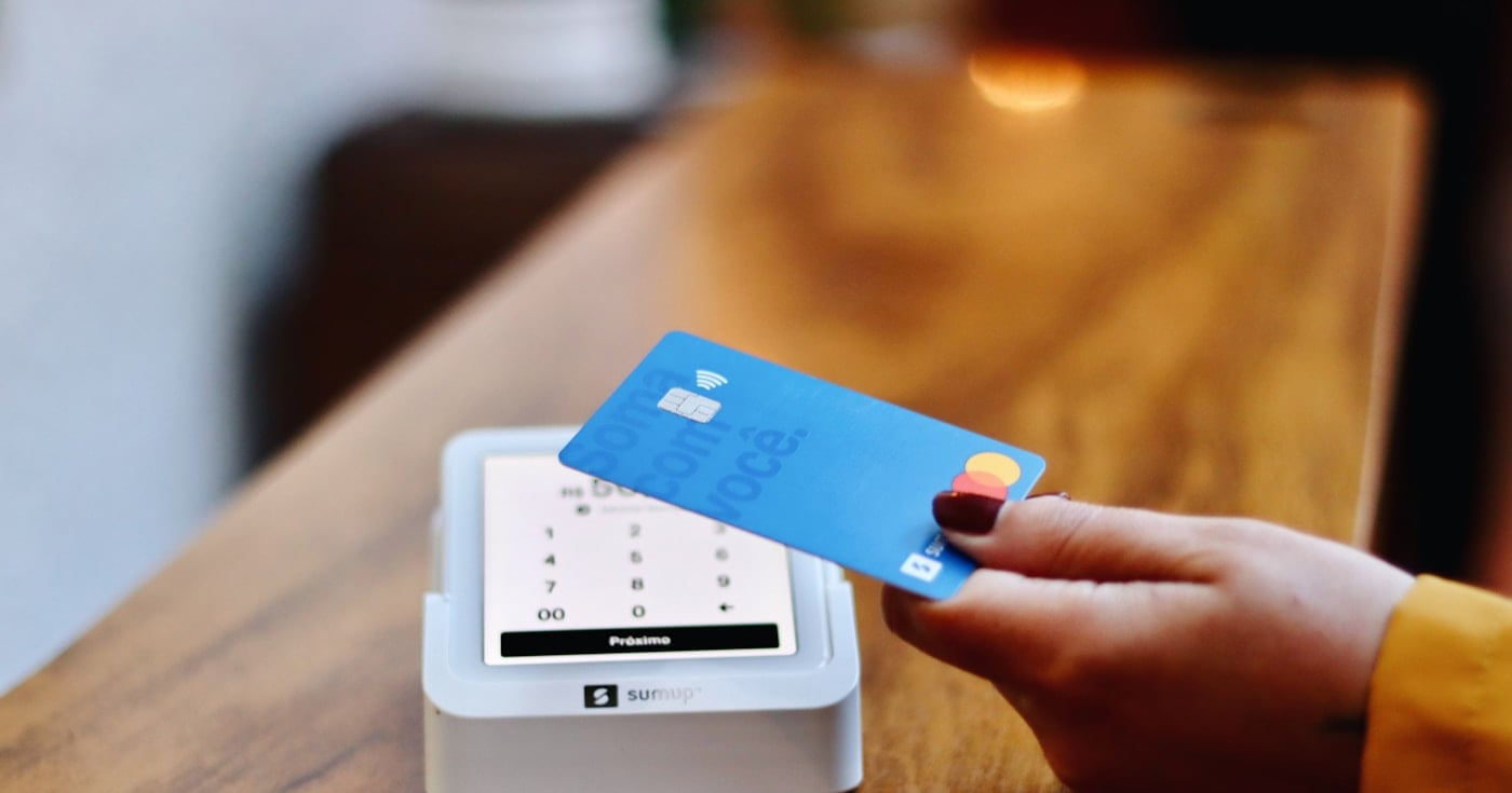 Person holding a credit card at payment terminal