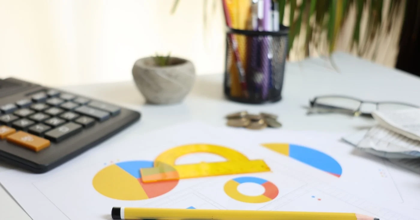 Desk with calculator and financial charts representing revenue model planning
